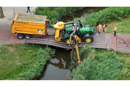 Tractor zakt door brug